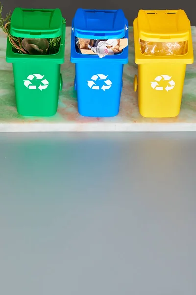 Три цветных контейнера для переработки, изометрическая проекция на сером фоне с копировальным пространством. Утилизационный знак на мусорных баках, синий, желтый и зеленый. Разделение отходов для снижения антропогенного давления . — стоковое фото