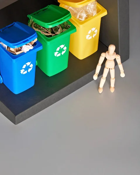 Wooden model of human and three color coded recycle bins, isometric projection with copy-space. Recycling sign on the bins, blue, yellow and green. Waste separation concept. — 图库照片