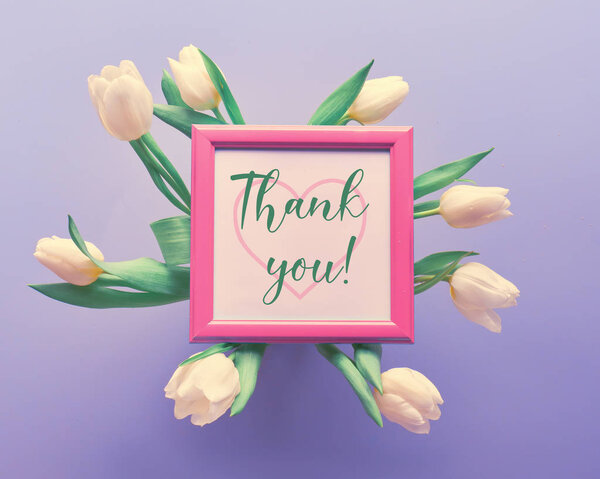 Весенний фон со словом "спасибо" с силуэтом сердца в розовой рамке в окружении белых тюльпанов на светло-фиолетовом градиентном фоне
.