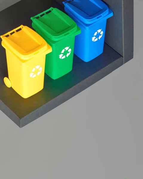 Three color coded recycle bins, isometric picture on grey paper, copy-space. Recycling sign on the bins, blue, yellow and green. Waste separation to minimize mixed waste and recycle paper and plastic. — Stock Photo, Image