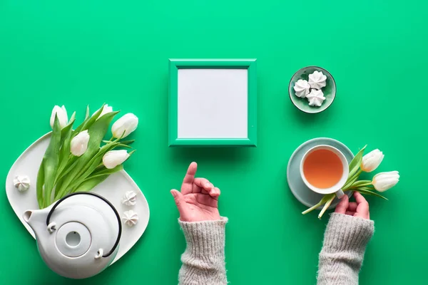 Geometric panoramic flat lay with hands. Tea cup, pot, sweets and white tulips on green. Valentine day, Mother's day, international women day March 8. Text space in frame, trendy top view — ストック写真