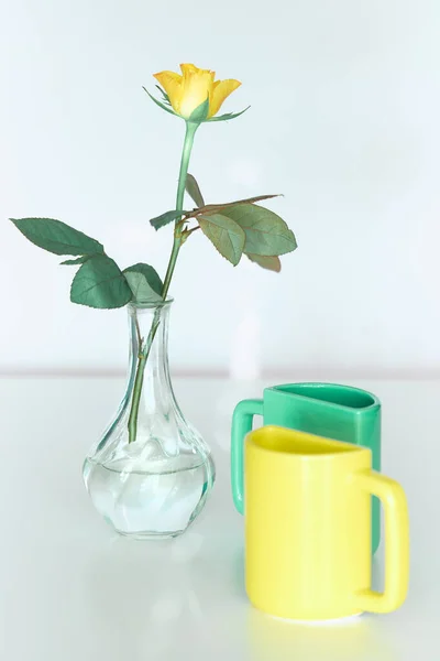 Yellow rose flower and twin pack half mugs in yellow and fresh mint green. Minimalist design for your house in bold colors. Modern interior decor, romantic gifts. Design for greeting card or poster.