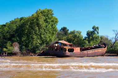 Tigra delta in Argentina, river system of the Parana Delta. Lush vegetation and old abandoned hull of rusty metal passenger or cargo ship. Lujan River delta system bringing water to Rio de la Plata. clipart