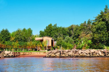Lush vegetation, wooden house and pier. Tigra delta in Argentina, river system of the Parana Delta North from capital city Buenos Aires. clipart