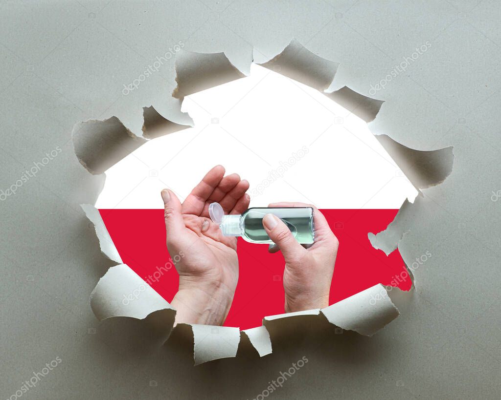 Poland fights against coronavirus. Hand hygiene with disinfection gel in paper hole with Polish flag as background. Hygiene measures, prevention of public health threat from viral pneumonia Covid-19.