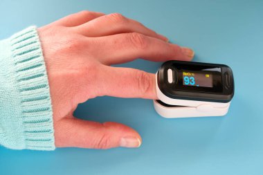 Nabız oksimetresi taşınabilir dijital cihaz kişinin oksijen doygunluğunu ölçmek için. Oksijendeki azalma acil durum işaretidir. Covid-19 'un ağır viral zatürresi. Cihaz Kafkas kadın elinde.
