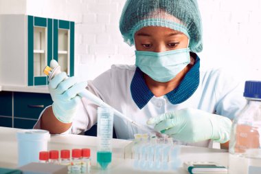 Koronavirüs için PCR testi. Beyaz önlüklü Afrikalı genç kadın teknolojisi, bilim adamı veya doktor hasta örneklerindeki SARS-CoV-2 'yi tespit etmek için nükleik asit testi yapar.