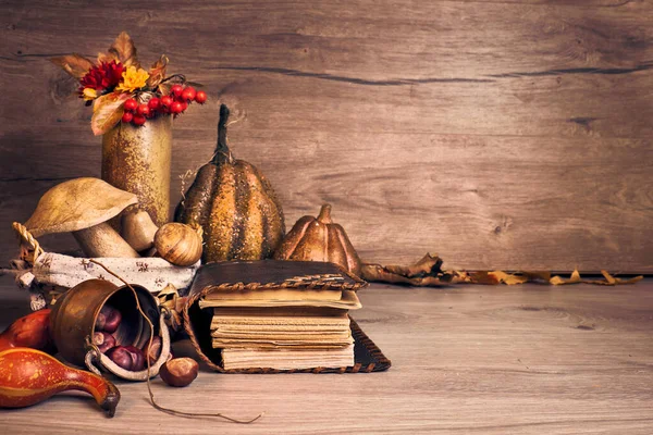 Autumn Thanksgiving arrangement with wooden mushrooms. Fall leaves, apples, peppers and chestnuts. Autumn still life arrangement indoors, old antique books on aged wooden table, copy-space.