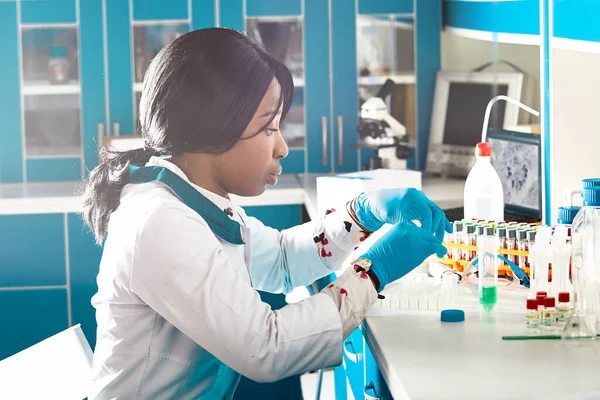 Laboratuvar önlüğü ve nitril eldivenli Afrikalı bilim adamı veya lisansüstü öğrencisi modern test laboratuvarında hasta örneklerini PCR testine tabi tutuyor..