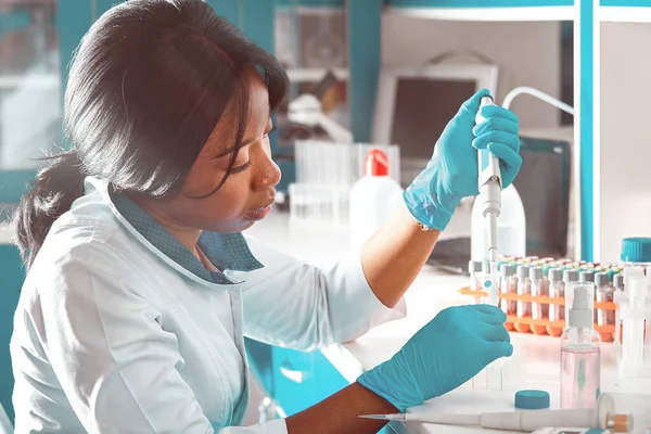 African scientist or graduate student in lab coat and protective wear performs PCR testing of patient samples in modern test laboratory. Troubleshooting pcr kits to diagnose Covid-19 patients.