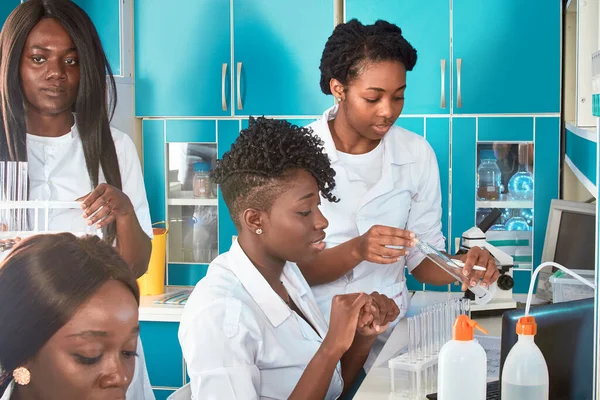 Female African medical students, young graduates in research, medical test lab performing various testing on samples. Microscopic analysis biopsy, pcr nucleic acid test for coronavirus.