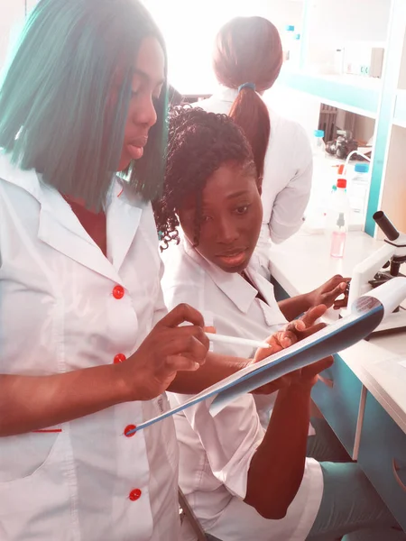 Female African medical students or scientists in research laboratory or medical test lab discuss work - testing and treating patients with Covid-19 disease caused by coronavirus.