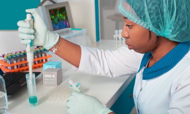 Afrikalı bilim adamı, teknik asistan veya laboratuvar önlüğü, tek kullanımlık şapka ve eldiven giyen mezun modern test laboratuarı içinde SARS-CoV-2 virüsü için PCR testini optimize ediyor. Nükleik asit testlerinin sorun çıkarması.