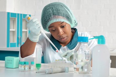 Afrikalı bilim adamı, laboratuvar önlüklü teknik asistan, koruyucu şapka ve eldiven modern test laboratuvarında SARS-CoV-2 virüsü için PCR testini optimize ediyor. Yeni koronavirüs için PCR testlerinde sorun..