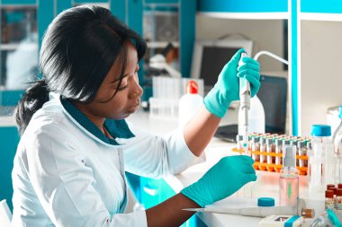 Laboratuvar önlüğü ve koruyucu giysi giyen Afrikalı bilim adamı veya lisansüstü öğrencisi modern test laboratuvarında hasta örneklerini PCR testine tabi tutuyor. Covid-19 hastalarına teşhis koymak için PCR kitlerinin sorun çıkarması.