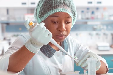Afrikalı bilim adamı, laboratuvar önlüklü teknik asistan, koruyucu şapka ve eldiven modern test laboratuvarında SARS-CoV-2 virüsü için PCR testini optimize ediyor. Nükleik asit testlerinin sorun çıkarması.