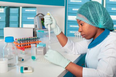 Nükleik asit testlerinin sorun çıkarması. Afrikalı bilim adamı, teknik asistan veya laboratuvar önlüğü, koruyucu şapka ve eldiven giyen mezun modern test laboratuvarında SARS-CoV-2 virüsü için PCR testini optimize ediyor.