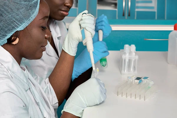 Afrikalı bilim adamları, laboratuvar önlüğü ve eldiven giyen teknik asistanlar veya mezunlar modern test laboratuvarında hasta örneklerini PCR testine tabi tutuyorlar. PCR kitleri sorun çıkarıyor, Covid-19 hastalarına teşhis koyuyor.