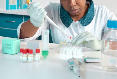 Afrikalı bilim adamı, laboratuvar önlüklü teknik asistan, koruyucu şapka ve eldiven test laboratuvarında SARS-CoV-2 virüsü için PCR testini optimize ediyor. Yeni koronavirüs için PCR testlerinde sorun..
