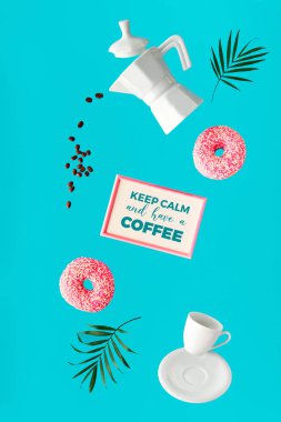 Havada asılı duran kahve ve çörekler. Kahve çekirdekleri uçuyor. Seramik kahve makinesi ve espresso bardağı. Palmiye yapraklarının yükselmesi ve çerçevede 