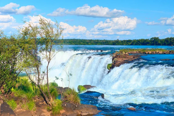 Arjantin 'de Iguazu şelaleleri, güneşli bir günde Şeytan Ağzı manzarası, bulutlu mavi gökyüzü. Iguazu nehrinin üstündeki buharlı suyun tepesine yakın çekim..