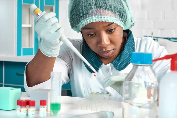 African scientist, technical assistant in lab coat, protective hat and gloves optimizes PCR testing for SARS-CoV-2 virus in modern test laboratory. Troubleshooting of nucleic acid tests.