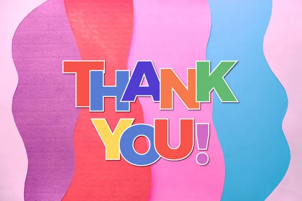 Thank you text in rainbow letters on layered colorful abstract paper background. Thank you doctors, nurses and essential key workers taking care of our life and well being during Covid-19 pandemics!