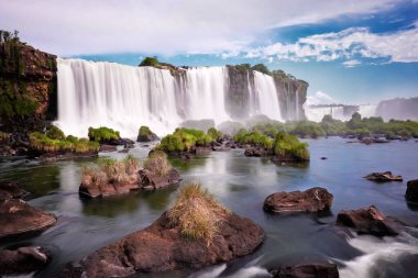 Arjantin 'de Iguazu şelaleleri, Şeytan Ağzı manzaralı. Sis ve bulutlarla dolu birçok görkemli ve güçlü su çağlayanlarının panoramik görüntüsü. Iguazu Vadisi 'nin panoramik görüntüsü. Suyun içinde ot ve taşlar var..