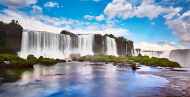 Arjantin 'de Iguazu şelaleleri, Şeytan Ağzı manzaralı. Sis ile çağlayan birçok görkemli ve güçlü suyun panoramik görüntüsü. Mavi gökyüzünün bulutlu yansıması ile panoramik görüntü.