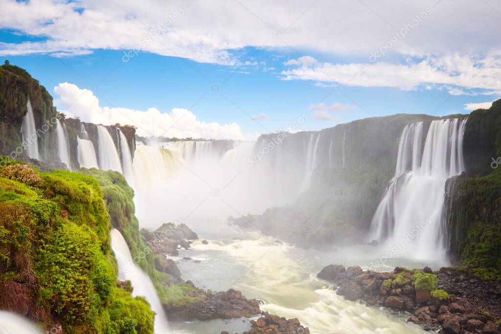 Iguazu waterfalls in Argentina, view from Devil's Mouth. Panoramic view of many majestic powerful water cascades with mist. Long exposure, long water. Panorama of Iguazu valley from above.