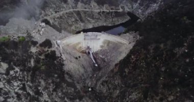 Bir göletin havadan çekilmiş görüntüsü dağların arasında akan suyla birlikte bir orman ve dolambaçlı bir yol tarafından engellenmiştir (Santa Anita Kanyonu, California, Usa)