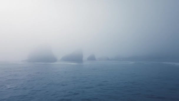 Câmera de drones se aproxima das rochas em densa névoa saliente do calmo oceano azul. Ariyas Beach, Oregon, EUA — Vídeo de Stock