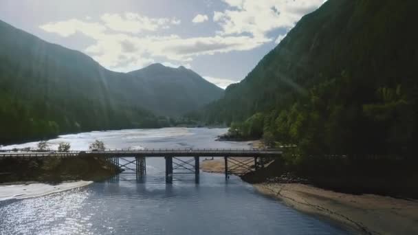 Drohne Kamera filmt eine Brücke über einen Fluss zwischen Bergen mit einem dichten Wald montana, USA — Stockvideo