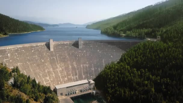 Flygfoto av floden, damm och reservoar mellan berg med tät skog Hungry Horse Dam, Flathead River, Montana, Usa — Stockvideo