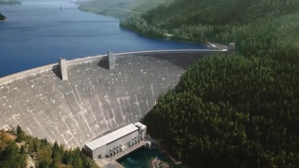 Câmera Drone movendo reservatório na frente de uma barragem no sopé de montanhas arborizadas Hungry Horse Dam, Flathead River, Montana, EUA — Vídeo de Stock