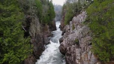 İnsansız hava aracı yoğun ormanlı bir dağ geçidinde akıntıya karşı ilerliyor. Aguasabon Şelalesi, Ontario, Kanada 