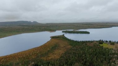 Ormanlık kıyılar, bir kulübe ve ufuktaki dağlar arasındaki gölün hava görüntüleri bulutlu bir günde Marie Louise Gölü, Ontario, Kanada 