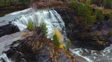 Yeşil Kaministiquia Nehri, Kakabeka Şelalesi, Ontario, Kanada arasında kaynayan şelale, kaya çıkıntısı ve parlak sarı ağacın hava görüntüleri 