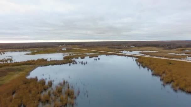 Imágenes aéreas de lago, matorral, carretera, pequeño asentamiento y horizonte nublado North Shoal Lake, Manitoba, Canadá — Vídeo de stock