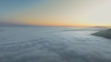 İnsansız hava aracı kameraları bulutların üzerinden uçuyor ve sabahın ilk ışıklarıyla Malibu Kanyonu, Calabasas, Kaliforniya, ABD 