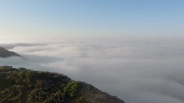 İnsansız hava aracı kamerası kanyonun uçurumundan sonsuz kalın bulutlara ve Malibu Kanyonu, Monte Nido, Kaliforniya, ABD 'deki gizemli sisli ufka doğru hareket ediyor. 