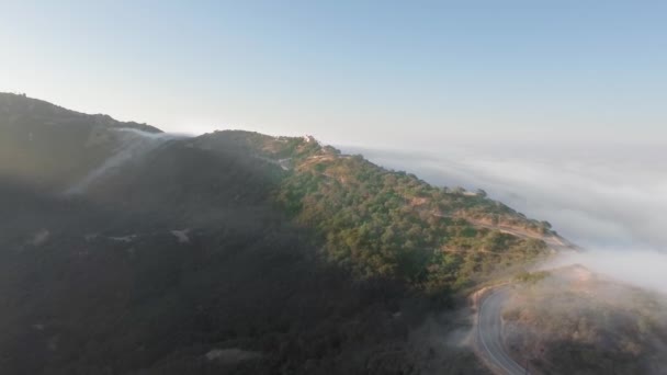 Vista aérea de um desfiladeiro e uma curva da estrada no sol matutino e nuvens abaixo de Malibu Canyon, Monte Nido, Califórnia, EUA — Vídeo de Stock