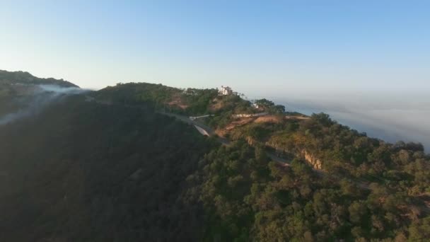 Aerial shot of a house by the road in a dense forest on top of a canyon, among the clouds in the morning sun Malibu Canyon, Monte Nido, California, USA — Stock Video
