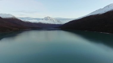 Alaska, Eklutna Gölü 'nde karla kaplı tepeleri olan dağlarla çevrili sakin bir göl manzarası.
