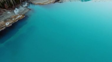 Havadan çekilen kameralar gölün hala masmavi yüzeyini ve Amerika 'nın Alaska eyaletindeki Eklutna Gölü' nün kıyısındaki karanlık ormanı gösteriyor.
