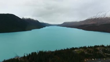 ABD 'nin Alaska eyaletindeki Eklutna Gölü' ndeki kar kaplı dağların arasındaki göl kıyısındaki yerleşim yerinin üzerindeki hava görüntüleri