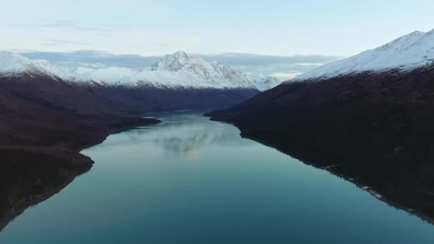 Drone strzela do jeziora lustrzanego z zalesionymi brzegami i zaśnieżonymi górami w spokojny dzień nad jeziorem Eklutna, Alaska, USA — Wideo stockowe