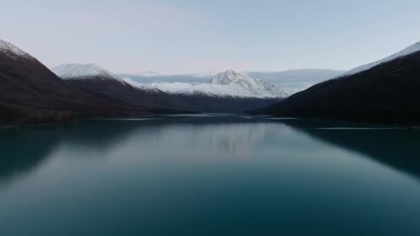 ドローンは、雪に覆われた山々の間で凍った湖を撮影します。 — ストック動画
