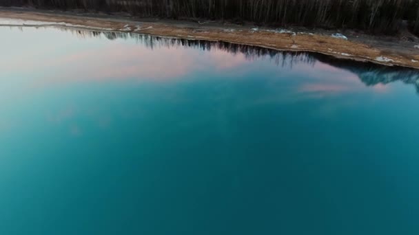 Letecký záběr oblohy a lesa v odrazu průzračně modré vodní hladiny, sníh leží na břehu jezera Eklutna, Aljaška, USA — Stock video