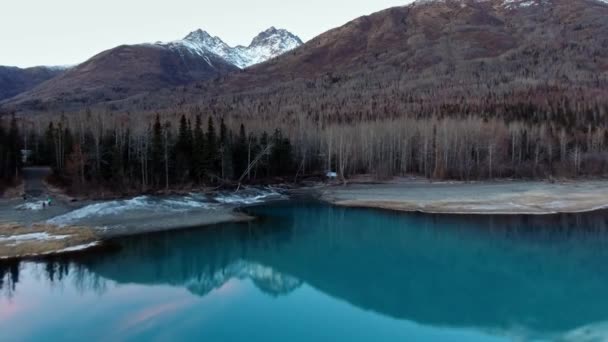 Dron se blíží k zimnímu lesu na břehu zrcadlového jezera, na úpatí hory u jezera Eklutna, Aljaška, USA — Stock video